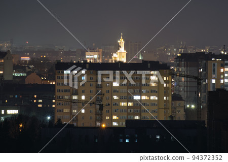Architectural details of modern high apartment buildings with many illuminated windows and balconies at night Architectural details of modern high apartment buildings with many illuminated windows and balconies at night 94372352