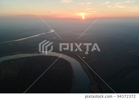 Aerial view of wide river flowing quietly in rural countryside in autumn evening 94372372