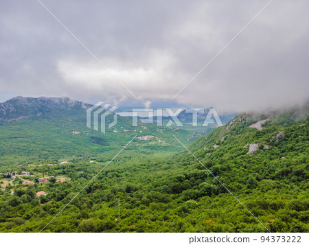 Beautiful view of the mountains of Montenegro and Skadar lake Portrait of a disgruntled girl sitting at a cafe table 94373222