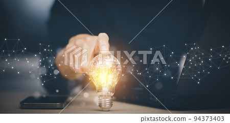 Businessman hand holding light bulb with icons and working on the desk, Creativity and innovation are keys to success.Concept of new idea and innovation with energy and power , working at home, 94373403