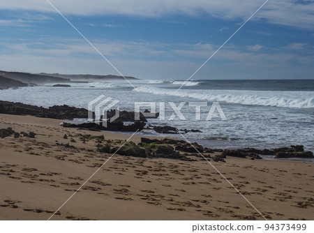 View of empty Praia da Ilha do Pessegueiro sand beach with ocean waves and sharp rock and cllifs at wild Rota Vicentina coast near Porto Covo, Portugal. 94373499