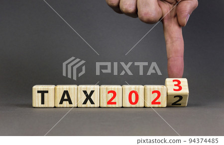 2023 tax new year symbol. Businessman turns a wooden cube and changes words Tax 2022 to Tax 2023. Beautiful grey table grey background, copy space. Business 2023 tax new year concept. 2023 tax new year symbol. Businessman turns a wooden cube and changes words Tax 2022 to Tax 2023. Beautiful grey table grey background, copy space. Business 2023 tax new year concept. 94374485