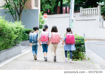 Elementary school students holding hands and walking on the sidewalk Elementary school students holding hands and walking on the sidewalk 94379244