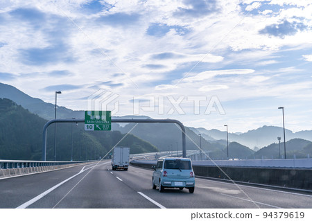 Trucks and passenger cars running on the Shin-Tomei Expressway in the morning, driving at the exit of the Shin-Shizuoka Interchange Trucks and passenger cars running on the Shin-Tomei Expressway in the morning, driving at the exit of the Shin-Shizuoka Interchange 94379619