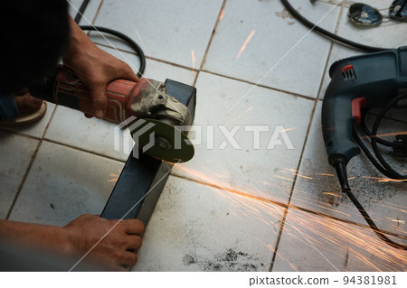 The contractor is using an electric grinder to decorate the steel welding point 94381981