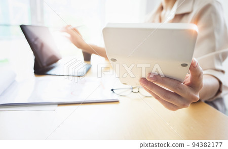Business woman using calculator to review balance sheet annual with holding pen and using laptop computer to calculating budget. audit and Check integrity before investment concept 94382177