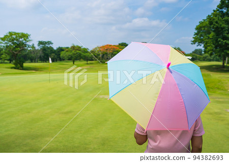 women Golfers under umbrella on green grass at golf course women Golfers under umbrella on green grass at golf course 94382693