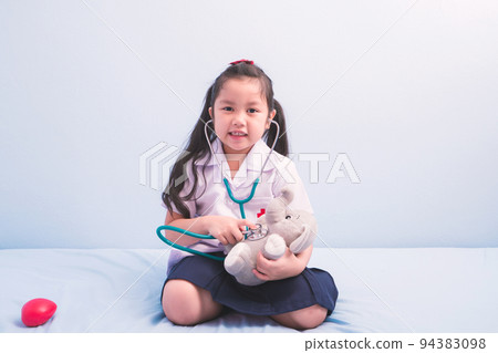 cute girls in medical uniform and stethoscope playing with a doll to be a doctor. child dreams of becoming a doctor career concept cute girls in medical uniform and stethoscope playing with a doll to be a doctor. child dreams of becoming a doctor career concept 94383098