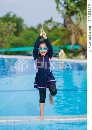 little girl smiling wearing swimming glasses in swimming pool. children playing in swimming pool on summer. little girl smiling wearing swimming glasses in swimming pool. children playing in swimming pool on summer. 94383109