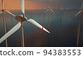 Large wind turbines with blades in field aerial view bright orange sunset blue sky wind park slow motion drone turn. Silhouettes windmills, large orange sun disc summer lens flare. Alternative energy 94383553