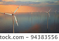 Large wind turbines with blades in field aerial view bright orange sunset blue sky wind park slow motion drone turn. Silhouettes windmills, large orange sun disc summer lens flare. Alternative energy 94383556