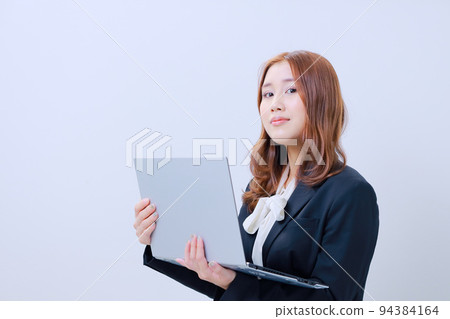 A young OL holding a laptop and making a smug face 94384164