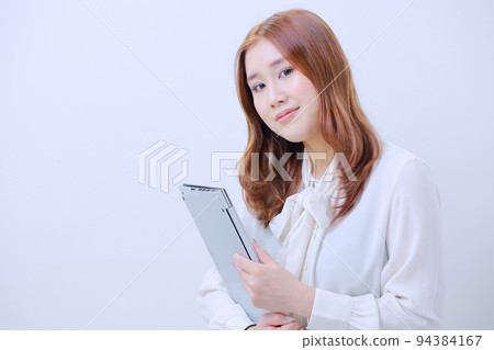 一個穿著白色襯衫的女人拿著筆記本電腦 一個穿著白色襯衫的女人拿著筆記本電腦 94384167