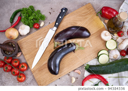 eggplant on wooden cutting board and vegetables at domestic kitchen eggplant on wooden cutting board and vegetables at domestic kitchen 94384336