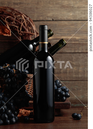 Red wine and blue grapes on an old wooden table. Red wine and blue grapes on an old wooden table. 94386027
