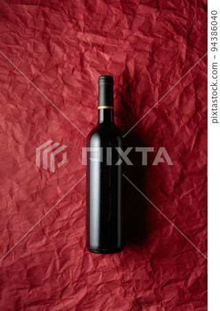 Bottle of red wine on a crumpled red paper background. Bottle of red wine on a crumpled red paper background. 94386040