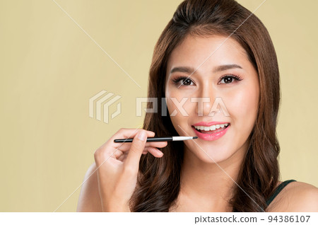 Young ardent female model with flawless beautiful skin using eyelash curler. 94386107