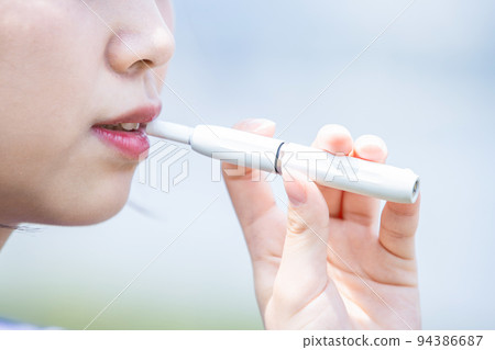 Young woman enjoying electronic cigarette Young woman enjoying electronic cigarette 94386687