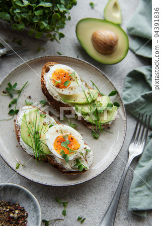 Bread toast, boiled eggs, avocado slice, microgreens on a plate Bread toast, boiled eggs, avocado slice, microgreens on a plate 94391836