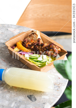 Fast food delivery.Greek souvlaki,salad and gyros take away menu from fastfood restaurant served in recyclable paper plates on table 94391913