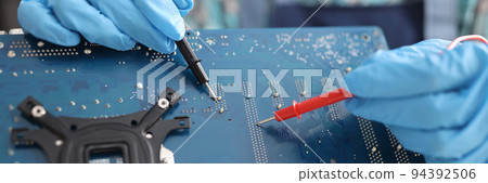 Repairman diagnosing breakdown in computer motherboard using tester closeup 94392506