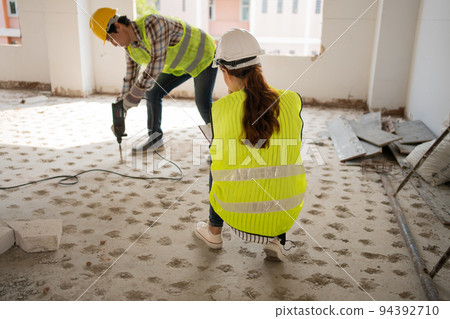 Engineer checking worker using an electric jackhammer to drill perforator equipment making holes before pouring the floor to be strong at construction site, Concept of worker and residential building Engineer checking worker using an electric jackhammer to drill perforator equipment making holes before pouring the floor to be strong at construction site, Concept of worker and residential building 94392710