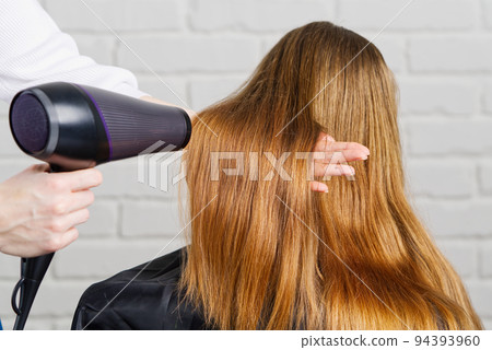 Beautiful young woman at the hairdresser blow drying her hair. Hair dryer in salon Beautiful young woman at the hairdresser blow drying her hair. Hair dryer in salon 94393960