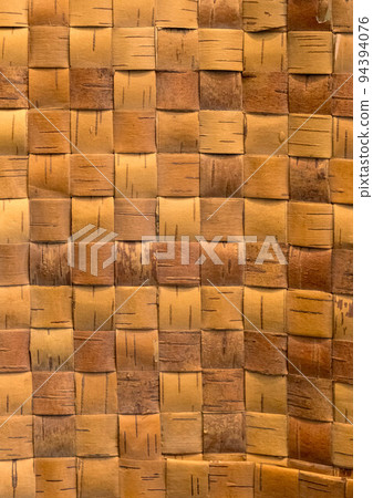 Wicker background from birch bark strips. Natural material. Texture of inner layers of birch bark of different colors with pattern of dark stripe 94394076