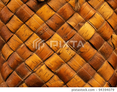 Wicker background from birch bark strips. Natural material. Texture of inner layers of birch bark of different colors with pattern of dark stripe 94394079