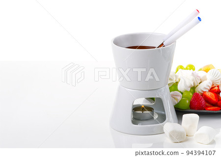 Chocolate fondue. fruits dipping into bowl with chocolate on white background Chocolate fondue. fruits dipping into bowl with chocolate on white background 94394107