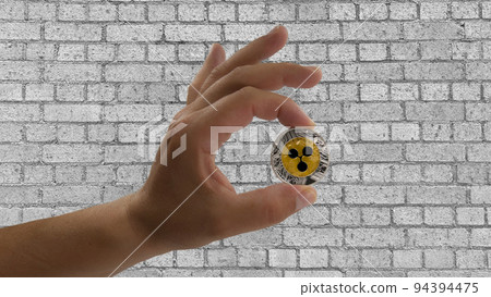 One hand holds the Ripple coin, the famous electronic money. In the background a black and white brick wall 94394475