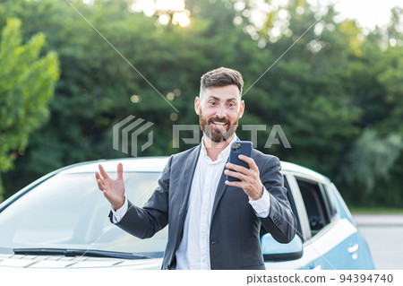 Successful and happy man brags about buying a new car, having fun talking to friends uses a video call in the phone app Successful and happy man brags about buying a new car, having fun talking to friends uses a video call in the phone app 94394740