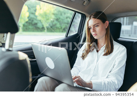 Beautiful female passenger car works on a laptop and uses a mobile phone Beautiful female passenger car works on a laptop and uses a mobile phone 94395354