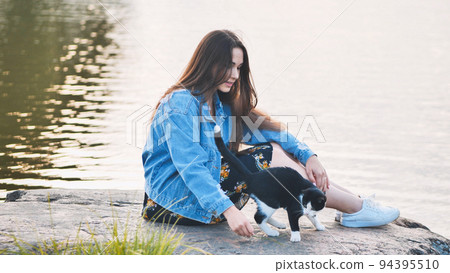 A girl plays with a cat by the lake. A girl plays with a cat by the lake. 94395510