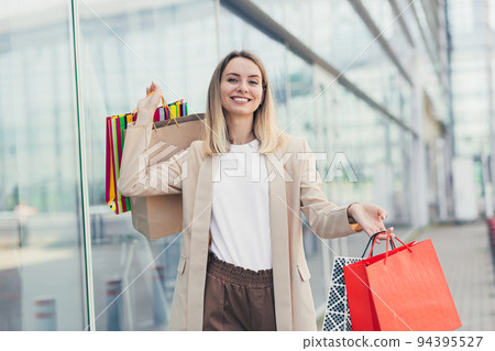 Woman with colored bags with goods near a modern shopping mall Woman with colored bags with goods near a modern shopping mall 94395527