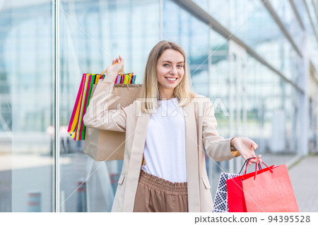 Woman with colored bags with goods near a modern shopping mall Woman with colored bags with goods near a modern shopping mall 94395528
