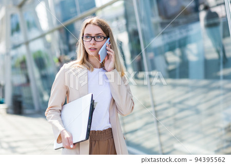 Young beautiful woman talking on a cell phone near the office, a businesswoman on a lunch break 94395562
