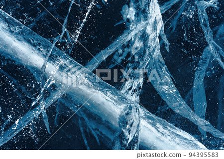 Transparent dark blue ice of frozen Baikal lake with white cracks pattern. Beautiful winter nature background. 94395583