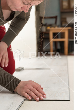 Installation of quartz vinyl floor, female master installs the floor. 94395885