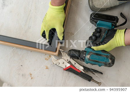 Drilling a hole in the door frame for a corner connection. 94395907