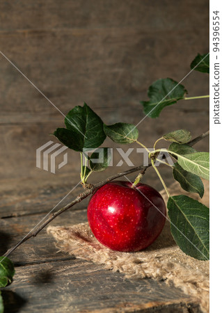 Red apple with leaves on burlap on wooden boards Red apple with leaves on burlap on wooden boards 94396554