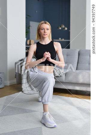 Woman performs lunges at home Woman performs lunges at home 94397749