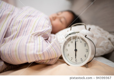 Sleeping child and bedside alarm clock Sleeping child and bedside alarm clock 94399367