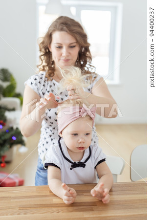 Mother doing hair for daughter with cochlear implant hearing aid - diversity concept. Innovative medical technologies 94400237
