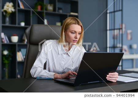 Young woman sitting at home office using laptop Young woman sitting at home office using laptop 94401994