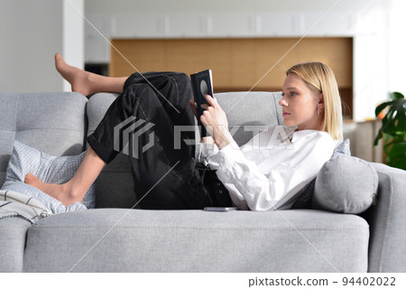 Woman lies on sofa and reads book 94402022