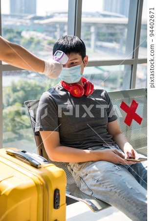Airport officer check temperature of young Asian man in terminal Airport officer check temperature of young Asian man in terminal 94402671