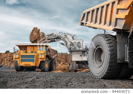 Large quarry dump truck and excavator. Big mining truck work coal deposit. Loading coal into body truck. Production useful minerals. Mining mining machinery to transport coal from open-pit production 94403071