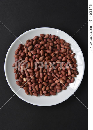 Peanuts on a white plate on a black background. Delicious nutty breakfast. Peanuts on a white plate on a black background. Delicious nutty breakfast. 94403366