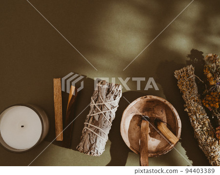 Items for spiritual cleansing - sage and flowers bundle, palo santo incense sticks, white candle on green background. Items for spiritual cleansing - sage and flowers bundle, palo santo incense sticks, white candle on green background. 94403389